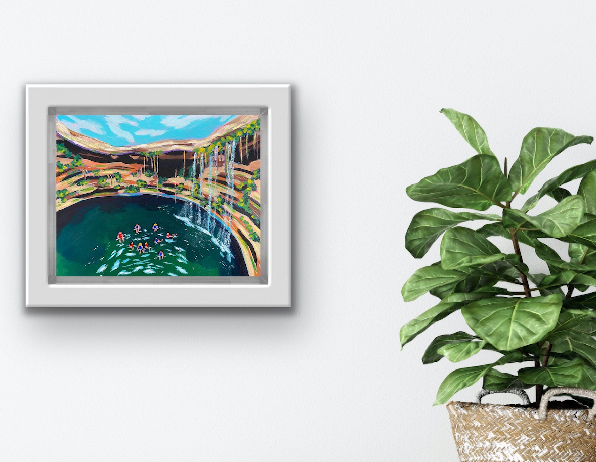 Travel Art "Cenotes" By Boston Artist Alexandra Wuyke hangs on a wall next to a plant.