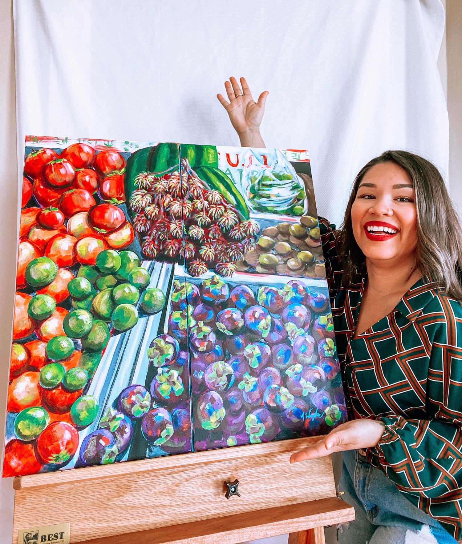 Alexandra Wuyke, St. Pete Acrylic Artist stands next to an original painting of a fruit stand in bold vibrant colors.